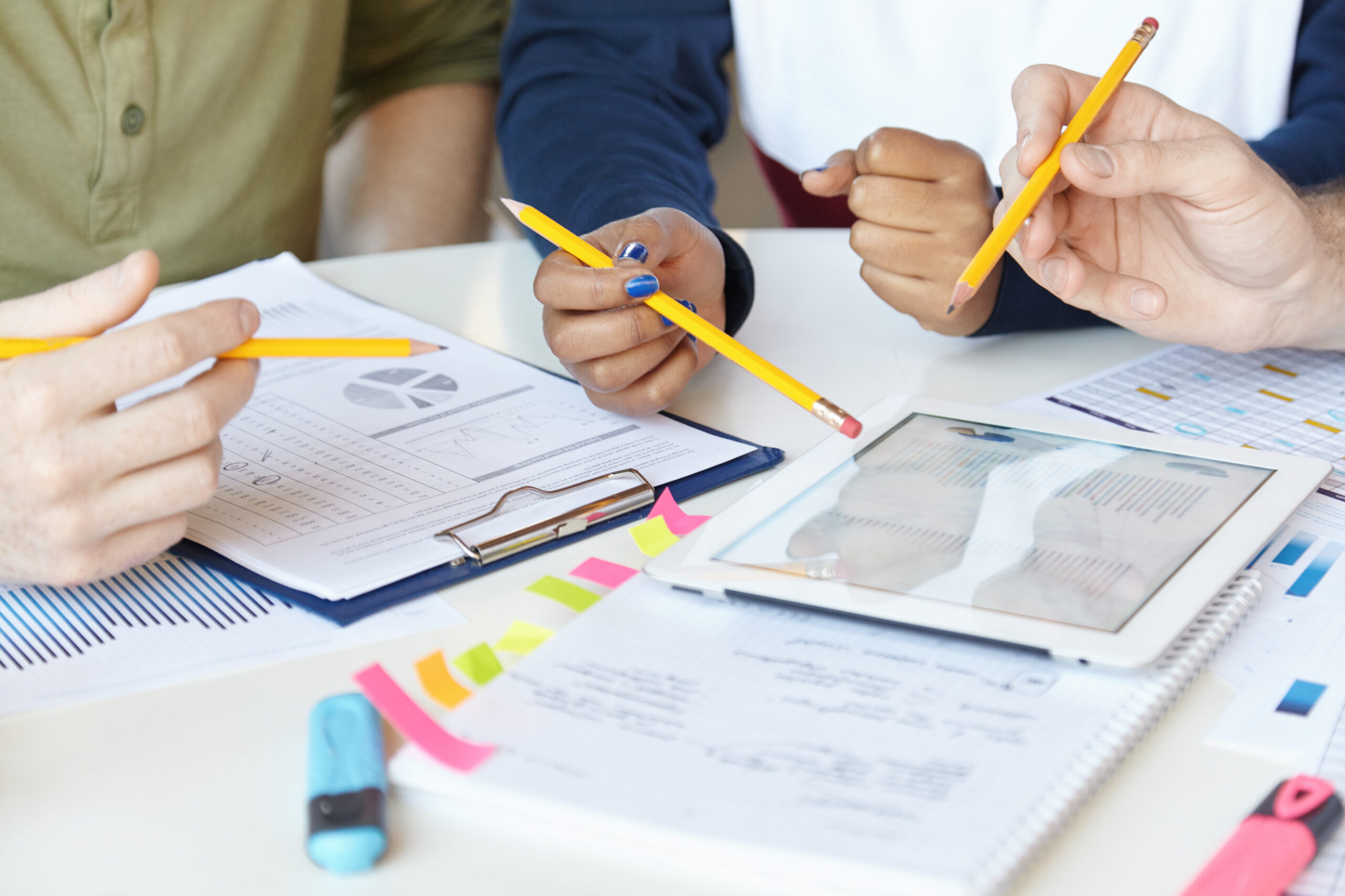 Collaborative work. Group of marketing experts working together on startup project, sitting at table with sheets of paper and digital tablet. Cropped shot of business people using touch pad for work